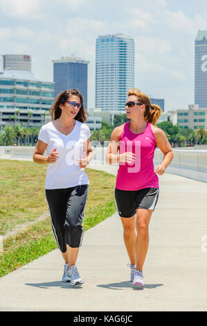 Due donne a fare jogging lungo il Bayshore Boulevard con il centro di Tampa, Florida, Stati Uniti d'America skyline in background. Foto Stock