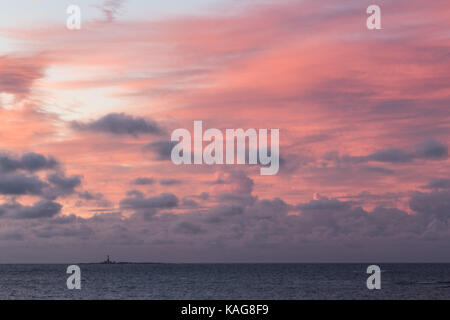 Sunrise con rosa Cielo e nubi ed un faro, faerder fyr, all'orizzonte. faerder national park, verdens ende, vestfold, Norvegia Foto Stock