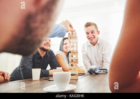 Gruppo di amici creativi seduti ad un tavolo di legno. persone avendo divertimento durante la riproduzione di un gioco da tavolo Foto Stock