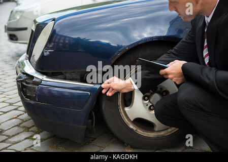 Agente di assicurazione ispezione vettura coinvolta in un incidente Foto Stock