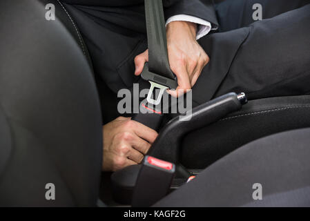 Close-up di un uomo seduto in auto il fissaggio della cintura di sicurezza Foto Stock