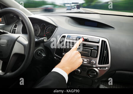Close-up di uomo di mano, premendo il pulsante di arresto di emergenza in auto Foto Stock