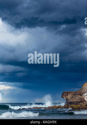 Onde si infrangono alte nella parte anteriore di un cielo blu a Warriewood Beach in NSW Australia Foto Stock