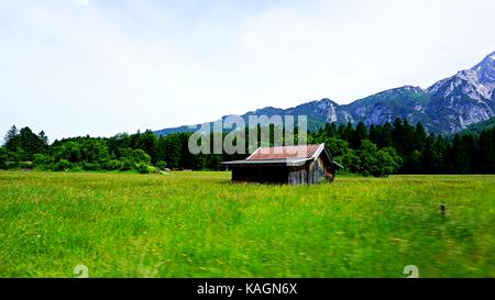 Un granaio house stand alone in campo verde con vista della montagna Zugspitze dietro, Grainau, Germania Foto Stock