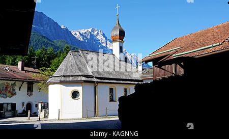 Grainau la chiesa e gli edifici con il massiccio dello Zugspitze dietro, Grainau, Germania Foto Stock