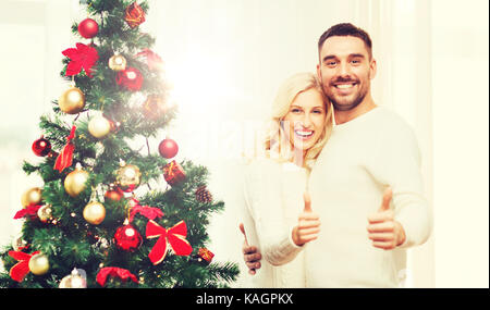 Coppia felice che mostra Thumbs up con albero di natale Foto Stock