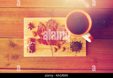 Tazza di tè, maple leaf e mandorla sul pannello di legno Foto Stock