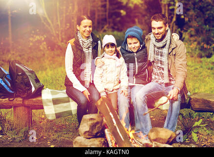 La famiglia felice seduta sul banco a fuoco di campo Foto Stock