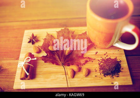 Tazza di tè, maple leaf e mandorla sul pannello di legno Foto Stock