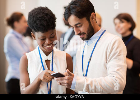 Coppia con smartphone a conferenze di affari Foto Stock