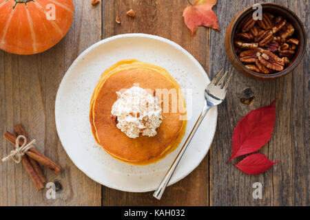 Frittelle di zucca con panna montata e cannella sul tavolo di legno. vista superiore, orizzontale Foto Stock