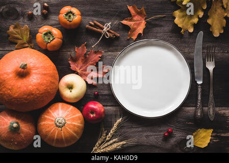 Autunnale di messa in tavola per la cena del Ringraziamento. piastra vuota, posate, zucche, mele e spezie su un tavolo di legno. cadere il concetto di cibo Foto Stock