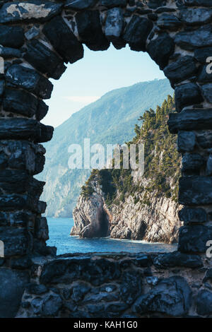 In pietra ad arco finestra che si affaccia sul pittoresco paesaggio del mar ligure e le montagne in Italia. sfondo di viaggio Foto Stock