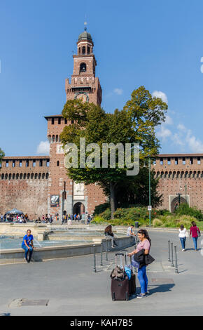 Un sorridente donna turistica (40-45) che è appena arrivato in città, di fronte al castello Sforzesco di Milano, lombardia, italia Foto Stock