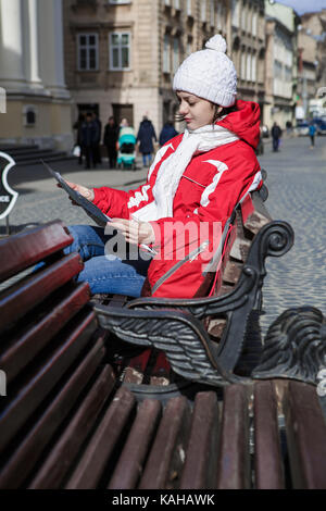 Donna turista è seduta su una panchina e guardando la mappa di una città in inverno Foto Stock
