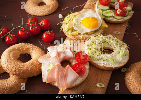 Varietà di panini su bagel: uovo, avocado, prosciutto, pomodoro, formaggio a pasta morbida, di germogli alfalfa Foto Stock