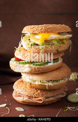 Varietà di panini su bagel: uovo, avocado, prosciutto, pomodoro, formaggio a pasta morbida, di germogli alfalfa Foto Stock