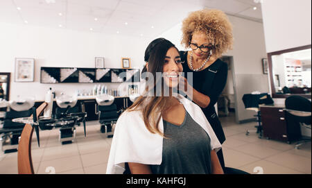 Donna parrucchiere a lavorare in salone. Giovane donna ottenendo un elegante taglio di capelli fatto a salon. Foto Stock