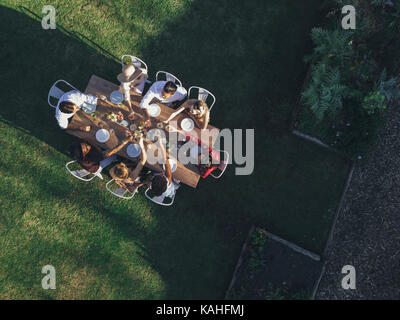 Vista aerea di amici la tostatura bevande al party all'aperto nel ristorante. Gruppo di persone sedute intorno ad un tavolo in giardino e avente bevande.. Foto Stock