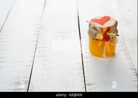 Dono un vasetto di miele su una tavola di legno Foto Stock