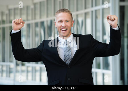 Successo giovane imprenditore entusiasta con il braccio sollevato Foto Stock