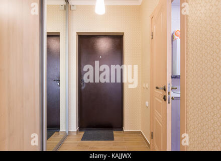 Corridoio al ingresso, interno, porta di ingresso, armadi a muro e una porta aperta per il bagno Foto Stock