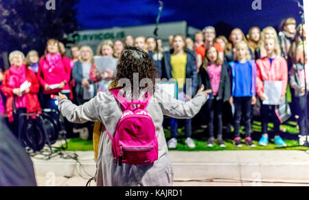 La donna conduce coro presso l'aria aperta evento nell'eveing, Cast, Doncaster, England, Regno Unito Foto Stock