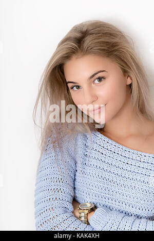 Ritratto di un giovane adolescente bionda ragazza in blu maglione isolati su sfondo bianco Foto Stock