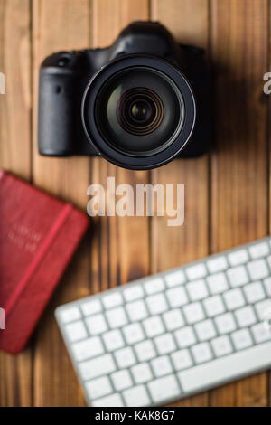 Telecamera digitale professionale e della tastiera del computer su un tavolo di legno. Foto Stock