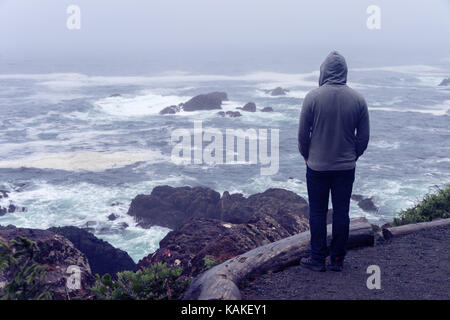 Lonely Man standing di fronte all'oceano pacifico e guardando il mare tempestoso sull'isola di Vancouver. Foto Stock