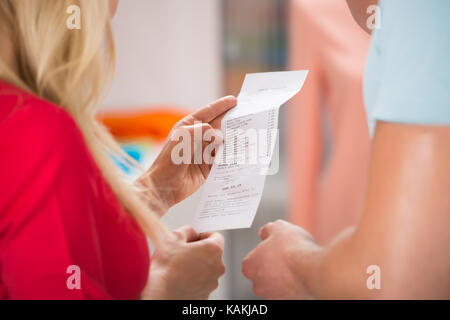 Immagine ritagliata della giovane con ricevuta di shopping in negozio Foto Stock