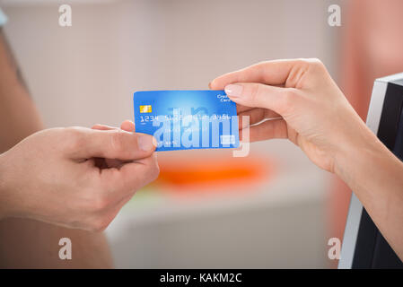 Immagine ritagliata del venditore di prendere carta di credito dal cliente femmina nel negozio di abbigliamento Foto Stock