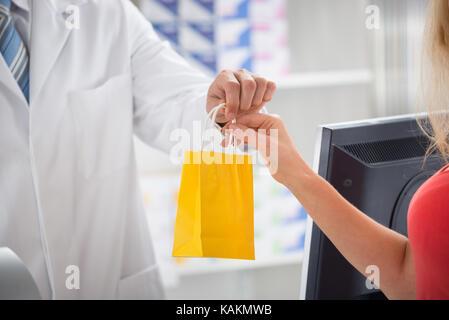 Sezione mediana del farmacista dare medicine a femmina cliente al negozio Foto Stock