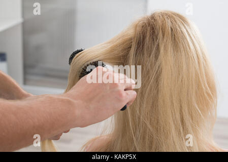 Immagine ritagliata del maschio di spazzolatura parrucchiere donna capelli al salon Foto Stock