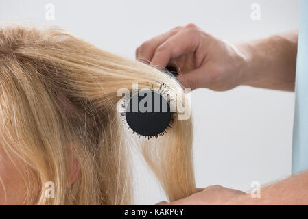 Immagine ritagliata del maschio di spazzolatura parrucchiere donna capelli al salon Foto Stock