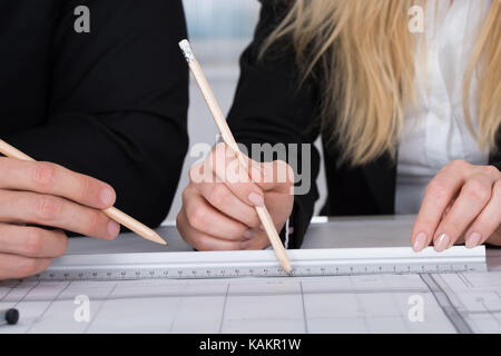 Immagine ritagliata di giovani uomini di affari che a discutere di un disegno architettonico Foto Stock