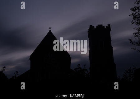 Una lunga esposizione di silhouette di una chiesa all'alba rendendo un pauroso, creepy, lugubre scena con nuvole sfocata Foto Stock