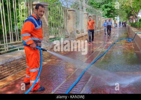 Far provincia, Shiraz, Iran - 19 aprile, 2017: street lavoratore lava il marciapiede, utilizzando un tubo flessibile collegato alla urbani idrico. Foto Stock