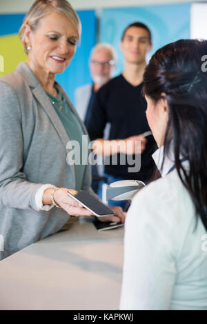 Aeroporto receptionist codice a barre a scansione su smart phone detenute da pas Foto Stock