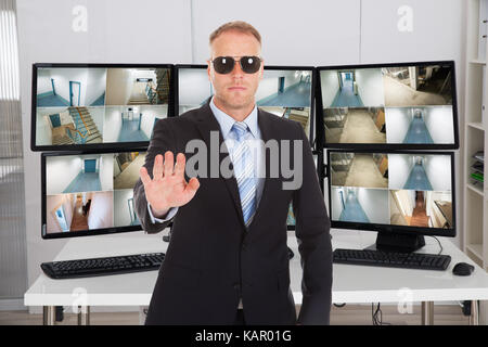 Ritratto di security manager gesti segno di arresto contro il monitor in ufficio Foto Stock