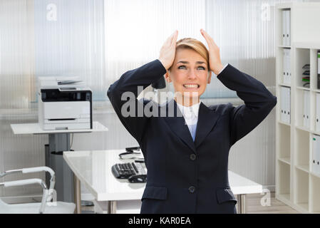 Frustrati giovane imprenditrice che soffrono di mal di testa in ufficio Foto Stock