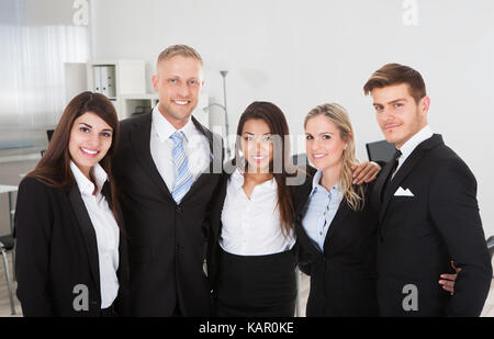 Ritratto di professionisti multietnica bracci permanente intorno a ogni altro in ufficio Foto Stock