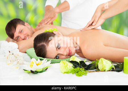 Ritratto di giovane sorridente giovane ricevere massaggio alla schiena a beauty spa Foto Stock