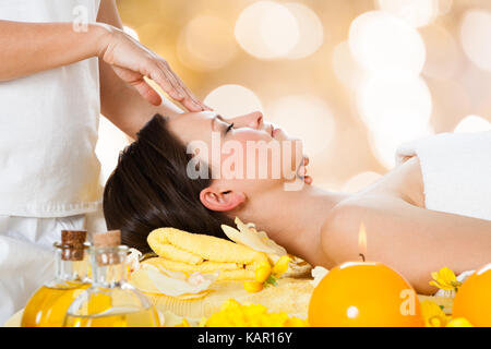 Vista laterale della giovane donna ricevere massaggio della testa dal massaggiatore in beauty spa Foto Stock