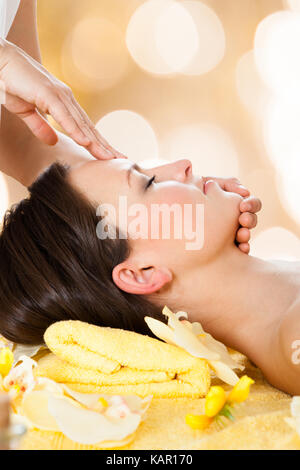 Vista laterale della giovane donna ricevere massaggio della testa dal massaggiatore in beauty spa Foto Stock