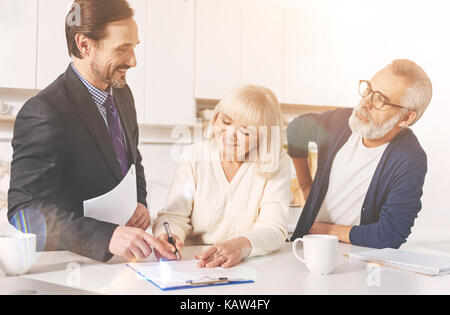 Coppia positiva firma le carte con agente di assicurazione Foto Stock