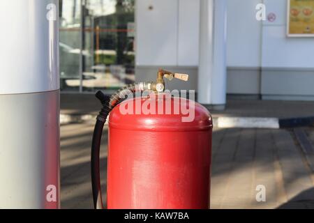 Red bombola di gas in piedi sul suolo in corrispondenza della stazione di gas. Foto Stock