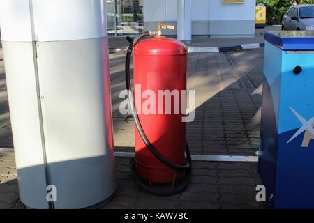 Red bombola di gas in piedi sul suolo in corrispondenza della stazione di gas. Foto Stock