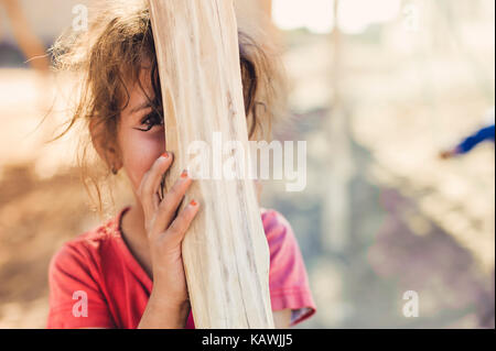 La ragazza si nasconde dietro un palo di legno Foto Stock