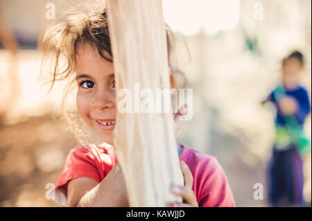 La ragazza si nasconde dietro un palo di legno Foto Stock